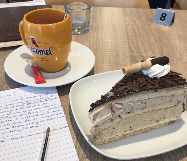 Part de gâteau à la crème au chocolat avec une tasse de Chocomel et un carnet où figure le début d'un article