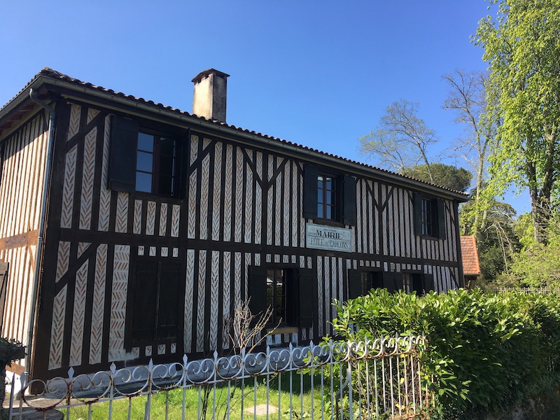 Vue sur une des maisons typique du village de Lévignacq avec ses colombages brun et son petit jardin