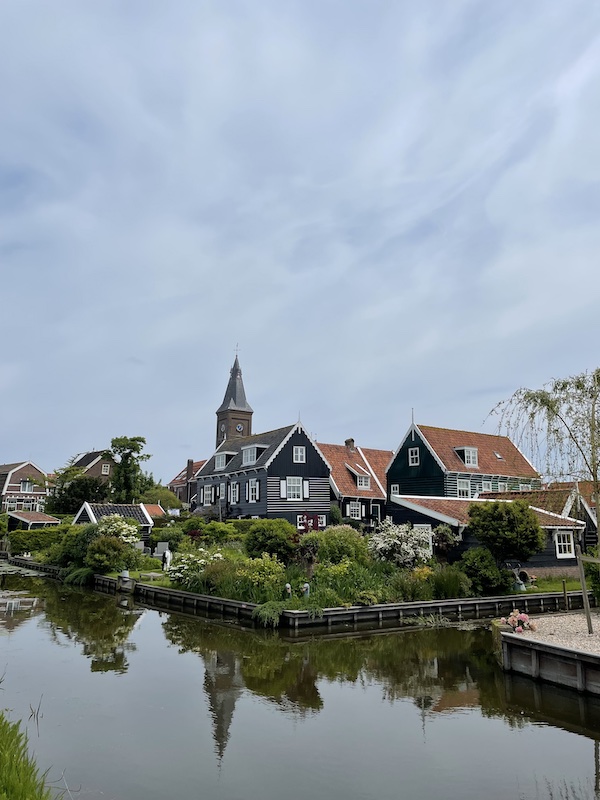 L'église de Marken aux Pays-Bas trône au milieu de petits canaux et de maisons en bois coloré vert ou noir.